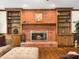 Cozy living room features brick fireplace with built-in shelving, hardwood floors, and natural light at 103 Lochwood West Dr, Cary, NC 27518