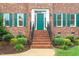 Close-up of brick home's entrance with a painted door, brick stairs, and manicured shrubbery at 103 Rose Sky Ct, Cary, NC 27513