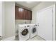 A laundry room with a full-sized washer and dryer, and overhead cabinets for storage at 10529 Sablewood Dr # 111, Raleigh, NC 27617