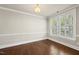 Spacious living room with a hardwood floor, crown molding, and a large window with shutter style blinds at 10529 Sablewood Dr # 111, Raleigh, NC 27617