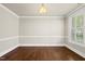 Spacious living room with a hardwood floor, crown molding, and a large window with shutter style blinds at 10529 Sablewood Dr # 111, Raleigh, NC 27617