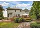 Backyard with two-story house, well-manicured greenery, patio and stone walkway at 106 Fawley Ct, Cary, NC 27519