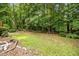 Grassy backyard with scattered leaves, bordered by trees, offering a serene outdoor space at 106 Fawley Ct, Cary, NC 27519