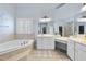 A luxurious bathroom featuring tile flooring, a garden tub, a large vanity, and ample lighting fixtures at 106 Painted Turtle Ln, Cary, NC 27519