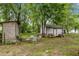 Large backyard featuring sheds, patio table, chairs, lush trees and grass at 1105 Hawthorne Ln, Burlington, NC 27215