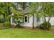 Side view of a cozy house with black shutters, a brick foundation, and landscaping at 1105 Hawthorne Ln, Burlington, NC 27215