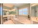 Bright bathroom featuring a soaking tub, glass enclosed shower, and double sink vanity at 119 Georgetowne Dr, Elon, NC 27244