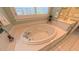 Close up on a soaking tub with chrome fixtures, tiled surround, and plantation shutters at 119 Georgetowne Dr, Elon, NC 27244