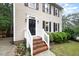Charming front entrance with brick steps, white railings, a black front door and mature landscaping at 12 Striding Ridge Ct, Durham, NC 27713