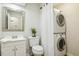Compact bathroom with modern stacked washer/dryer, decorative mirror, and neutral tones at 120 Jo Anne Cir, Cary, NC 27513