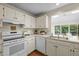Cozy kitchen with white cabinets, laminate countertops, and modern appliances next to a view to the sunroom at 122 Blackcherry Ln, Chapel Hill, NC 27514