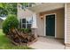 Close-up of a welcoming front porch with a green door, stylish column, and landscaped flower bed at 1310 Silver Dr, Mebane, NC 27302