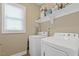 Well-equipped laundry room with washer, dryer, and shelving for organized storage at 1374 Patriot Points Way, Fuquay Varina, NC 27526