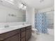Bright bathroom with double vanity, a mirror, and tub with blue patterned curtain at 146 Bent Willow Dr, Clayton, NC 27527