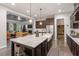 Open-concept kitchen with a large island, dark wood cabinets, and stainless steel appliances, flowing into the living area at 1508 Banks Brooke Dr, Raleigh, NC 27603