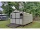A white metal storage shed with a set of double doors and two windows, sitting on a lush green lawn at 2012 Stadium Dr, Durham, NC 27705