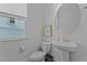 Well-lit powder room featuring a pedestal sink, round mirror, and modern fixtures at 2012 Sweet Samson St, Wake Forest, NC 27587