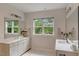 Bright bathroom with double sinks, white cabinets, and large windows offering serene outdoor views at 2426 Heron Watch Pl, Fuquay Varina, NC 27526