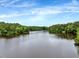 Beautiful lake surrounded by lush green trees and a clear blue sky at 2426 Heron Watch Pl, Fuquay Varina, NC 27526