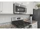 Close-up of a kitchen with stainless steel appliances and elegant granite countertops and white cabinetry at 260 Amber Acorn Ave, Raleigh, NC 27603