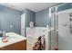 Well-lit bathroom with double sinks, tiled shower, bathtub, and blue accent wall at 300 Gilman Ln # 101, Raleigh, NC 27610