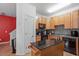 Well-lit kitchen features wood cabinets, black appliances, backsplash, and an island with granite countertop at 300 Gilman Ln # 101, Raleigh, NC 27610