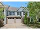 Two-story townhome featuring stone accents, gray siding, and a two-car garage, set against a blue sky at 3002 Bartlett Cir, Hillsborough, NC 27278