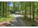 Gravel driveway leading to a charming home nestled among lush green trees at 305 Old School Rd, Chapel Hill, NC 27516