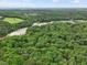 Aerial view of lush green forest with a river and distant view of a community at 305 Springtree Circle Cir, Fuquay Varina, NC 27526
