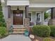 Inviting front porch with stone pillars, wooden rocking chairs, and a dark wood front door at 305 Springtree Circle Cir, Fuquay Varina, NC 27526