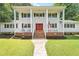 Charming two-story home featuring a white exterior, front porch, red door and well-maintained lawn at 307 Country Club Dr, Durham, NC 27712