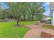 Scenic backyard showcasing a brick patio with outdoor seating, set amidst a spacious lawn and mature trees at 314 Lane Rd, Dunn, NC 28334