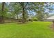 Large, green backyard with mature trees and a wooden fence, creating a private and peaceful outdoor space at 314 Lane Rd, Dunn, NC 28334