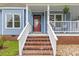 Charming front porch with brick steps, a vibrant red door, and classic white railings at 314 Lane Rd, Dunn, NC 28334