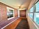 Sun room with brick walls, hardwood floors, ceiling fan, and ample natural light through multiple windows at 3810 Pendergrass St, Durham, NC 27704