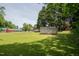 Lush backyard featuring a metal storage shed surrounded by mature trees and green grass at 424 Camp Rd, Burlington, NC 27217