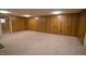 Expansive basement space with wood-paneled walls and soft carpet flooring at 424 Camp Rd, Burlington, NC 27217