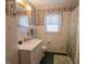 Charming bathroom with vintage-style wallpaper, a white vanity, and a window for natural light at 424 Camp Rd, Burlington, NC 27217