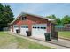 View of three car garage with white doors and red brick exterior at 424 Camp Rd, Burlington, NC 27217