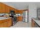 Well-lit kitchen featuring stainless steel appliances, tile floors, and natural wood cabinets at 4408 Jordan Oaks Way, Raleigh, NC 27604