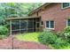 Brick home's backyard showcases a screened-in porch and beautiful landscaping at 4521 Chicopee Trl, Durham, NC 27707