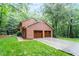 Brick home exterior showcasing a two-car garage, lush green lawn, and mature trees at 4521 Chicopee Trl, Durham, NC 27707