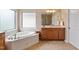 Bright bathroom featuring a separate tub, wood cabinets, and shower with a spacious double window at 5003 Blue Jack Oak Dr, Cary, NC 27519