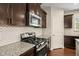 Modern kitchen with granite countertops, stainless steel gas range, and dark wood cabinets at 5011 Peachtree Town Ln, Knightdale, NC 27545
