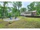Backyard showcases a stone patio with Adirondack chairs and a verdant lawn near the home at 5121 Raintree Rd, Durham, NC 27712