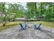 Outdoor space with a stone patio, complemented by blue chairs, plus lush greenery and the home's exterior at 5121 Raintree Rd, Durham, NC 27712