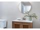Bathroom vanity with natural wood, white marble countertop, modern faucet, and a round decorative mirror at 5121 Raintree Rd, Durham, NC 27712