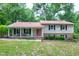 Traditional two-story home with a welcoming front porch, black shutters and a red front door surrounded by a lush lawn at 5121 Raintree Rd, Durham, NC 27712