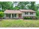 Traditional two-story home with a welcoming front porch, black shutters and a red front door surrounded by a lush lawn at 5121 Raintree Rd, Durham, NC 27712