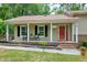 Charming front porch with seating, black shutters and a red front door, perfect for enjoying the outdoors at 5121 Raintree Rd, Durham, NC 27712